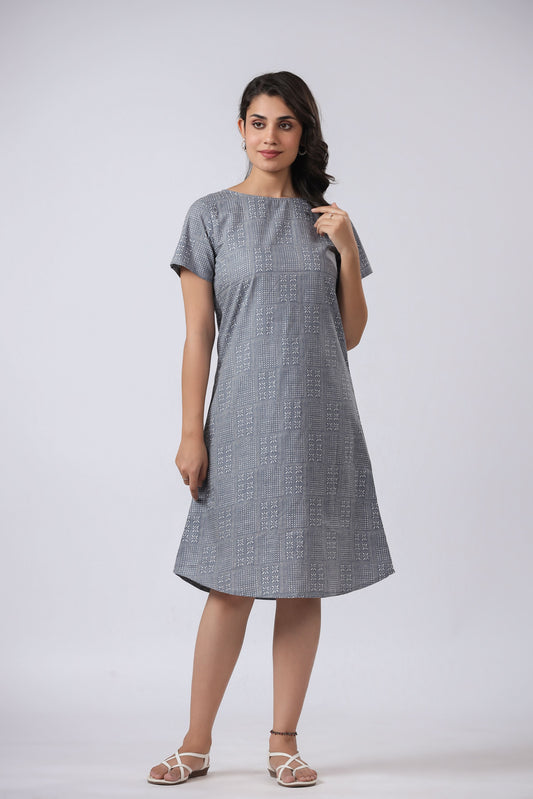 A woman standing and wearing a gray, short-sleeved, V-neck night dress with a relaxed fit.