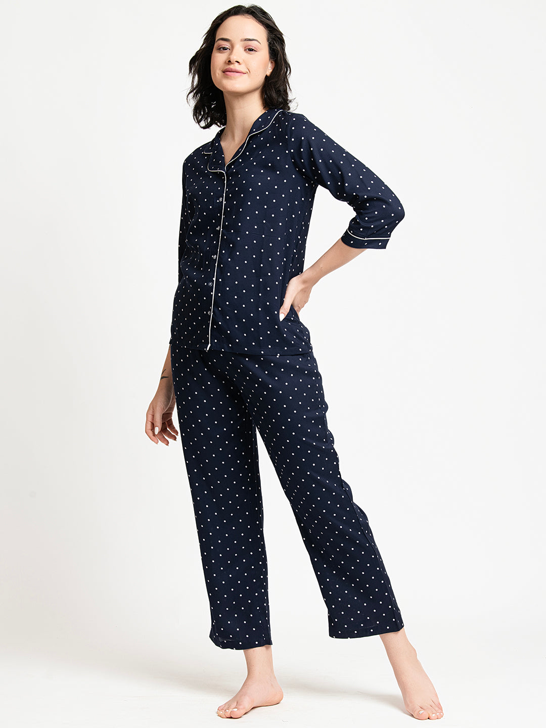 Woman wearing a navy blue polka dot pajama set on a white background