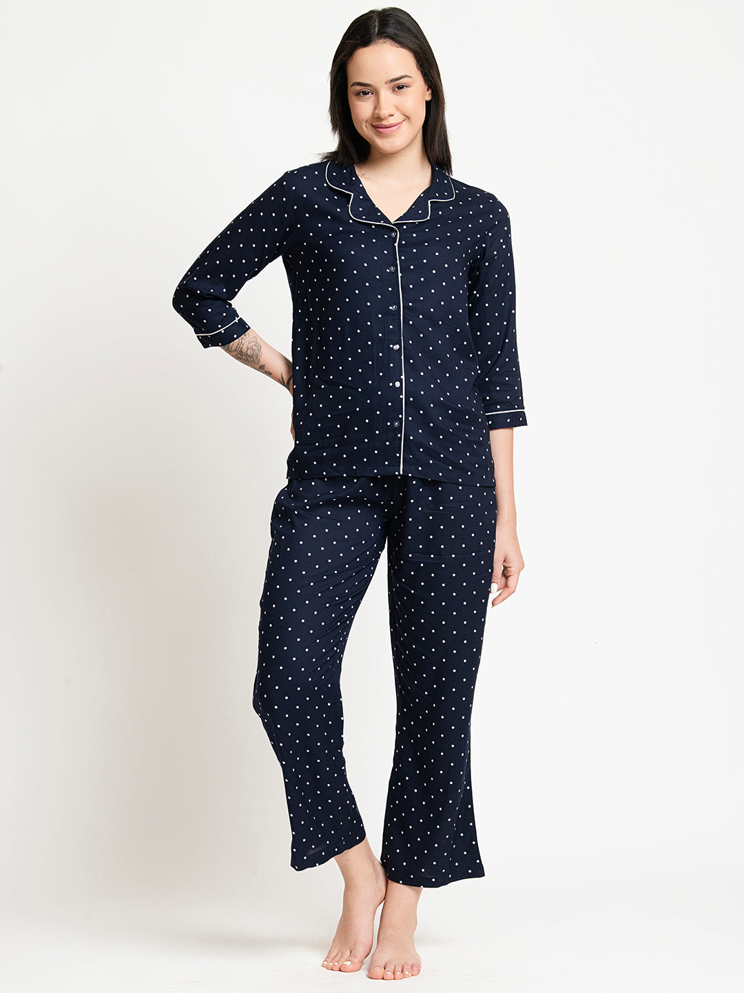 Woman wearing a navy blue polka dot pajama set on a white background