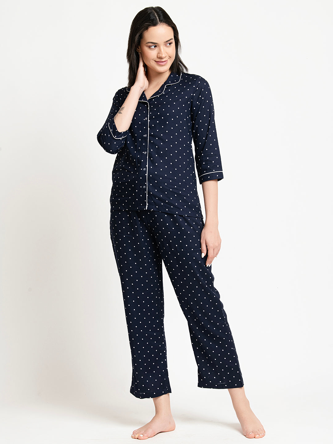 Woman wearing navy blue polka dot pajamas on a white background