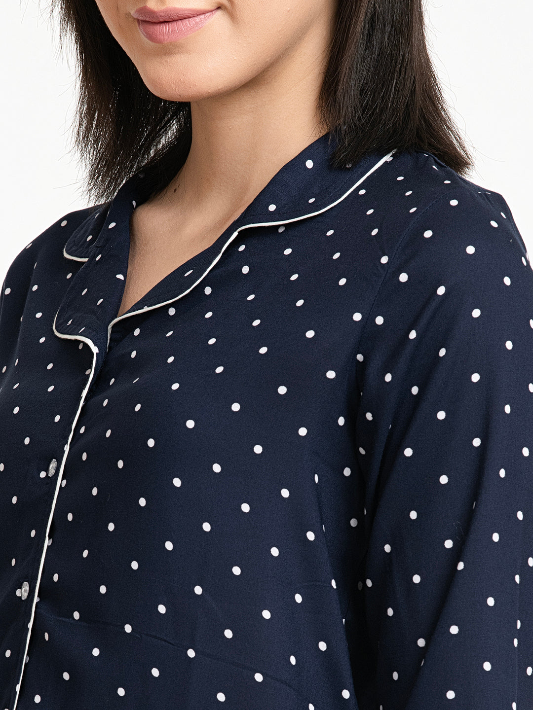 Navy blue pajama top with white polka dots worn by a person.